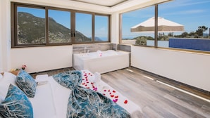 A modern bathroom with a bathtub, large windows, and a view of the mountains. - Villas Bella (Kas)