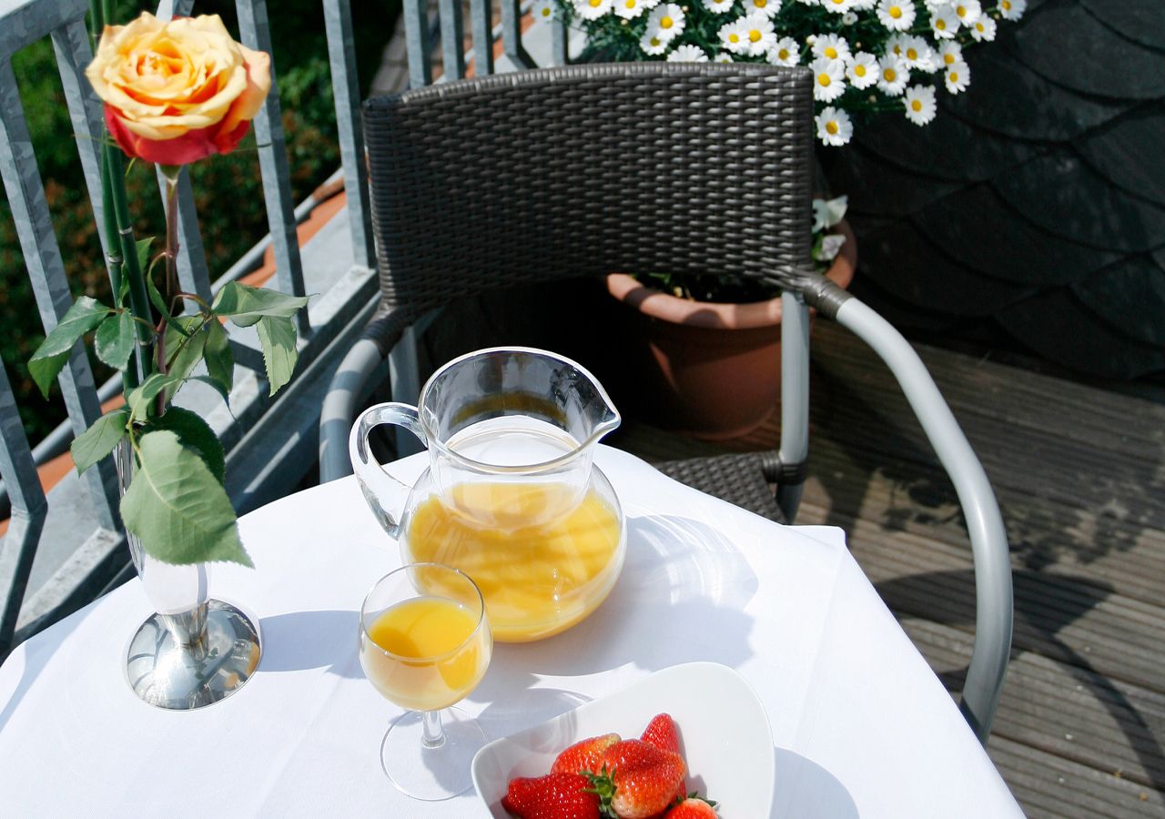 A table with a pitcher of juice, a glass of juice, and a bowl of strawberries.