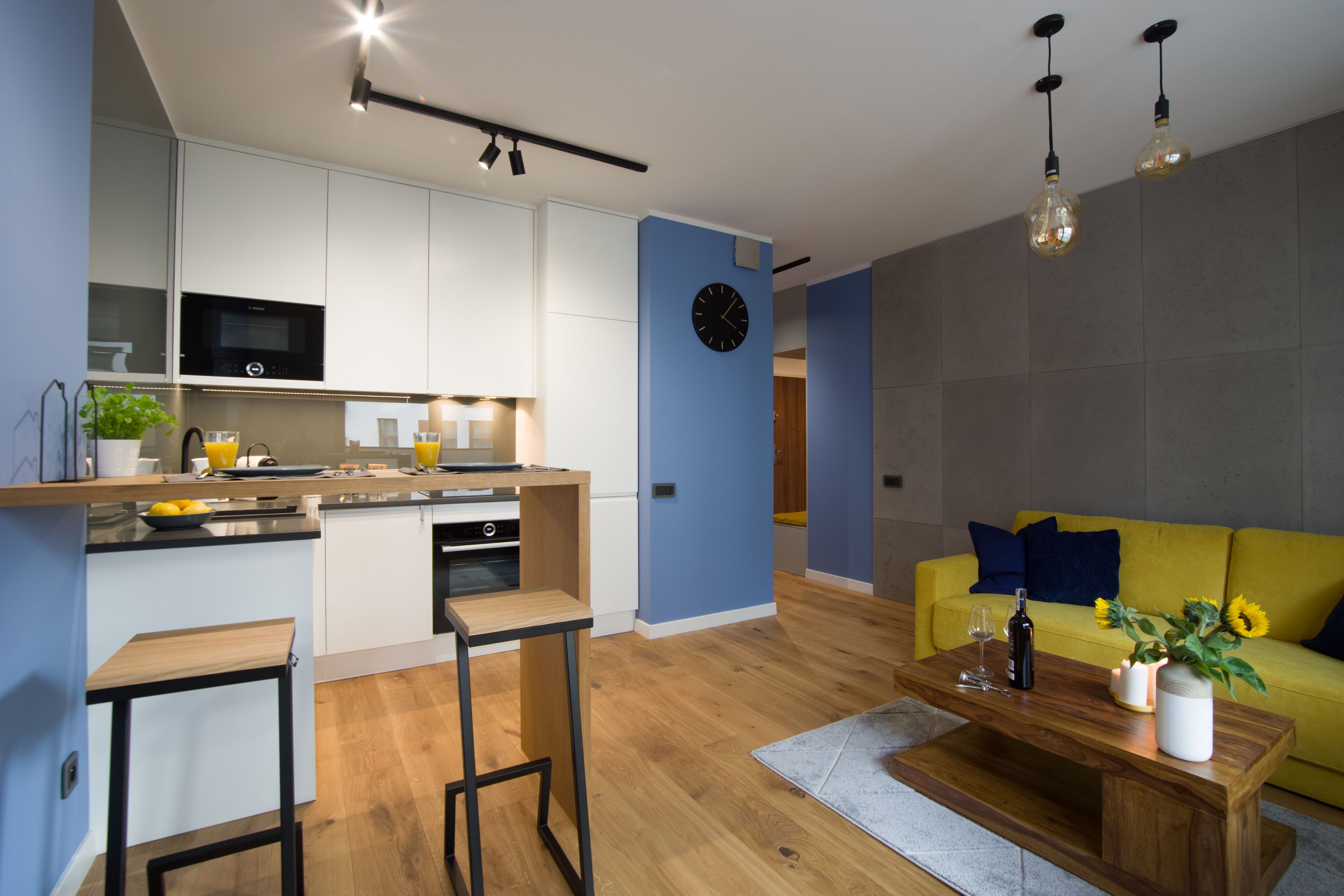 A modern kitchen with white cabinets, a built-in microwave, and a wooden island.