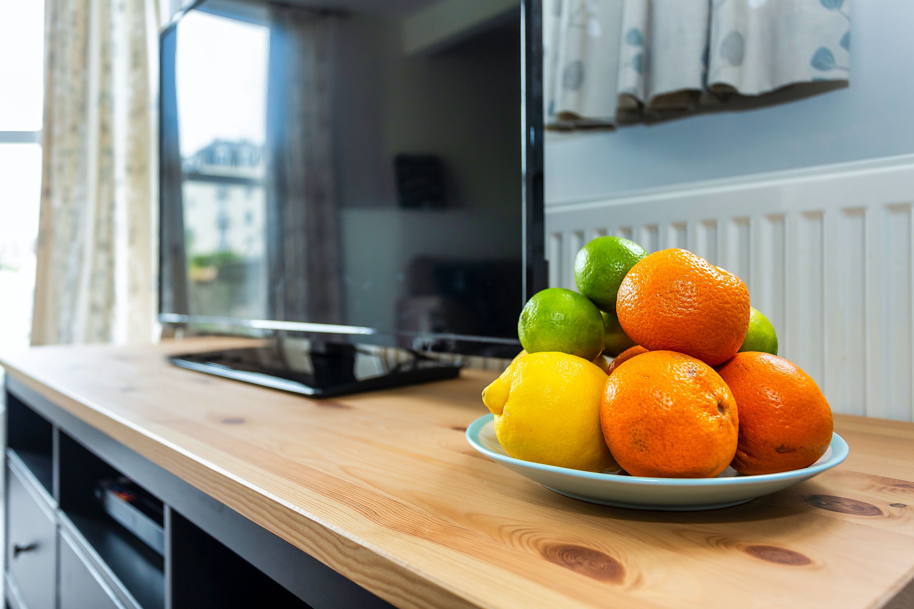 A kitchen counter with a plate of oranges and lemons.