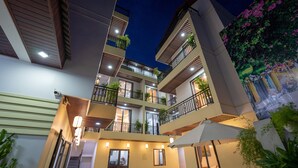A multi-story hotel with balconies, outdoor seating, and a reflective pool. - Hoi An Paradise Villa (Da Nang)