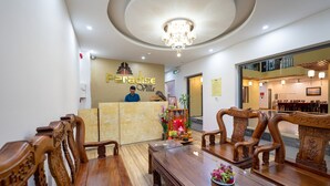 A reception area with a reception desk, a chandelier, and wooden furniture. - Hoi An Paradise Villa (Da Nang)