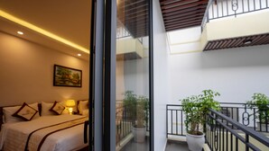 A hotel room with a bed, a nightstand, a lamp, and a painting on the wall. - Hoi An Paradise Villa (Da Nang)