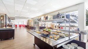 A buffet area with a variety of food items and a view of a snowy landscape through large windows. - Belambra Clubs Gourette - Lou Sarri (Eaux-Bonnes)