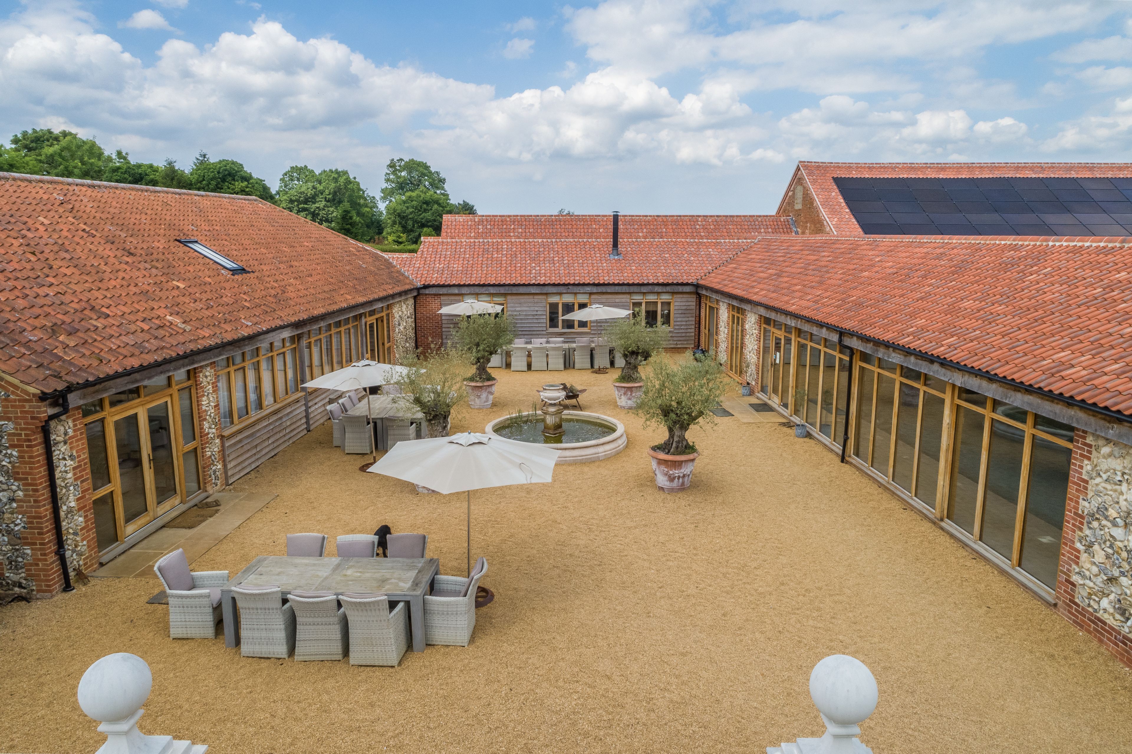 A courtyard with a dining area, potted plants, and a fountain.