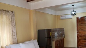 Une chambre avec un lit en bois, un coin cuisine et une structure de plafond en bois.