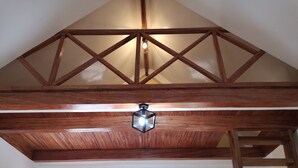 Une pièce dotée d’une structure de plafond en bois, d’un luminaire de style lanterne et d’une échelle.
