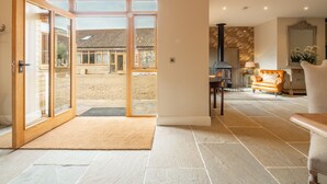 A spacious living area with a large sliding glass door leading to a courtyard, a fireplace, and a comfortable seating area. - Hill Farm Massingham, Little Massingham, Norfolk (Little Massingham)