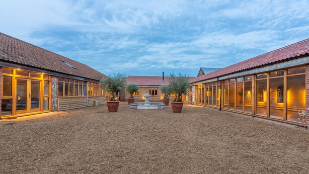 A courtyard with a fountain, potted plants, and a building with large windows and a tiled roof. - Hill Farm Massingham, Little Massingham, Norfolk (Little Massingham)