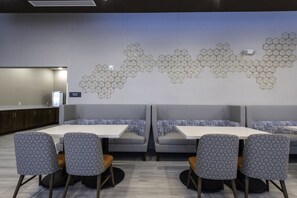 A modern dining area with hexagonal wall art, a counter, and seating with patterned chairs. - Comfort Suites Greenville Airport (Greenville)
