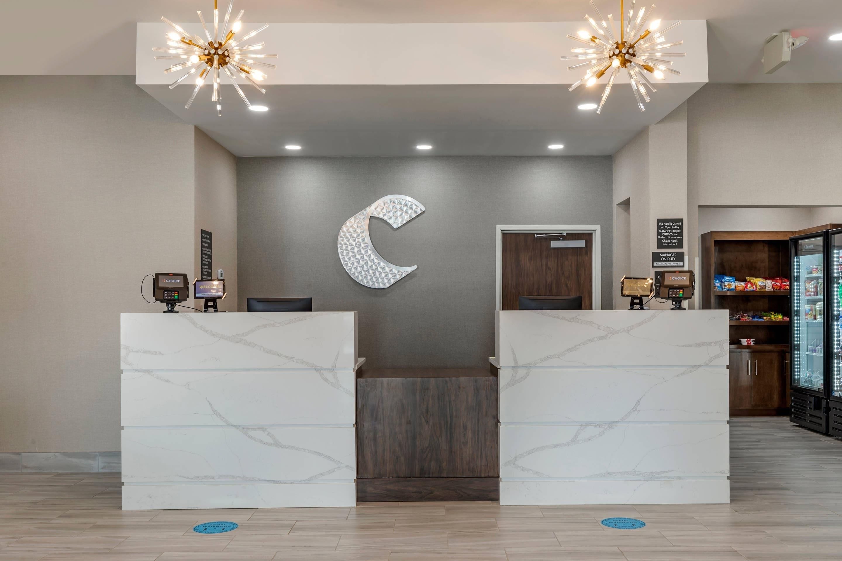 Zona de recepción de un hotel con mostradores de mármol, una decoración de gran luna colgante y un minibar.