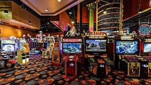 Ein Spielsalon mit verschiedenen Spielautomaten und einem bunten Teppich.