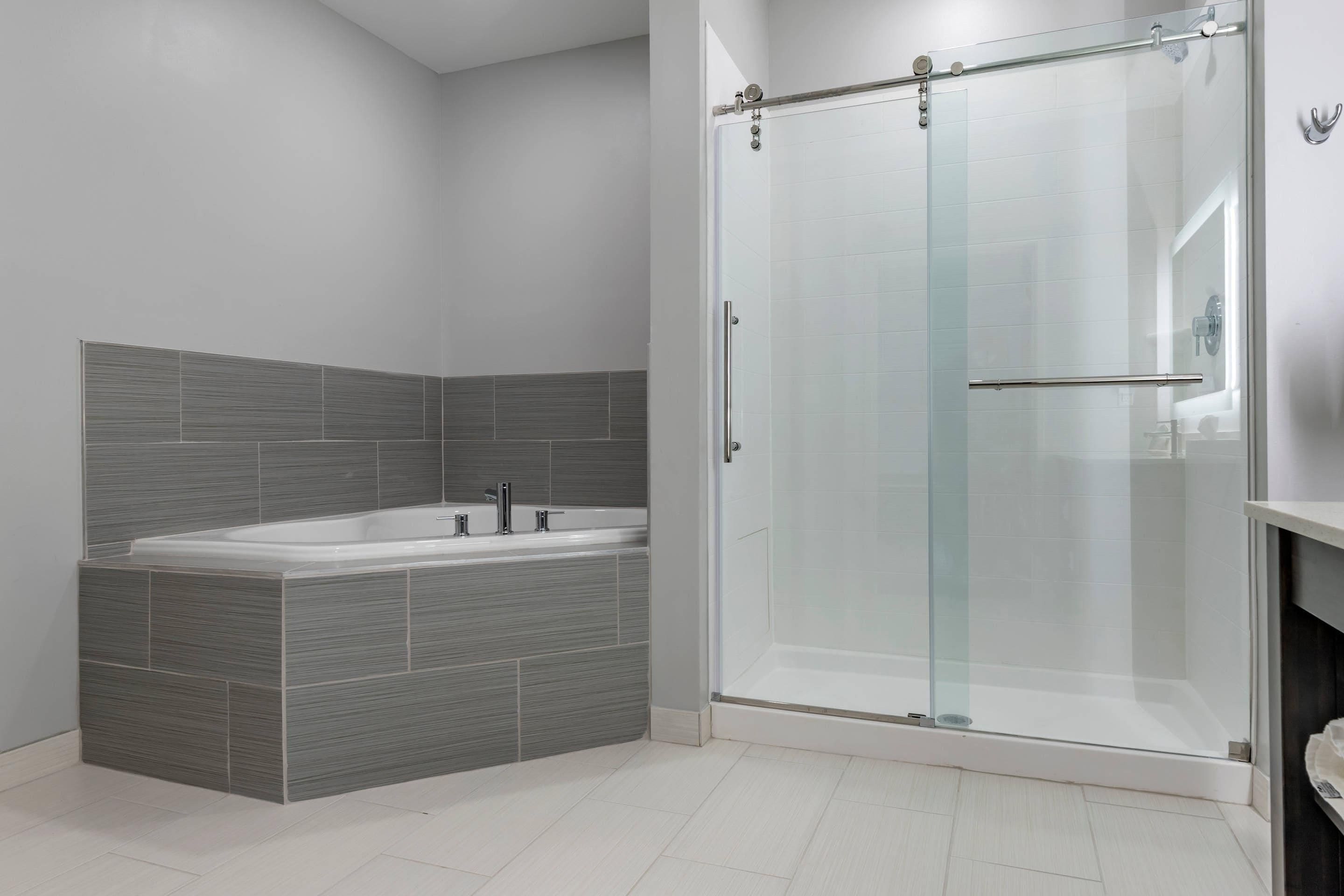 A modern bathroom with a glass-enclosed shower, a freestanding bathtub, and a tiled wall.