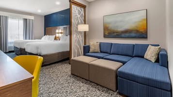 A hotel room with a bed, a sofa, a small table, and a chair.