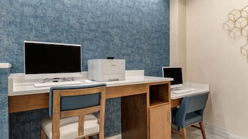Un escritorio moderno con dos sillas, una impresora y un monitor de computadora.