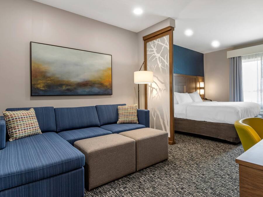 Een hotelkamer met een blauwe bank, een bed, een bureau en een groot raam.