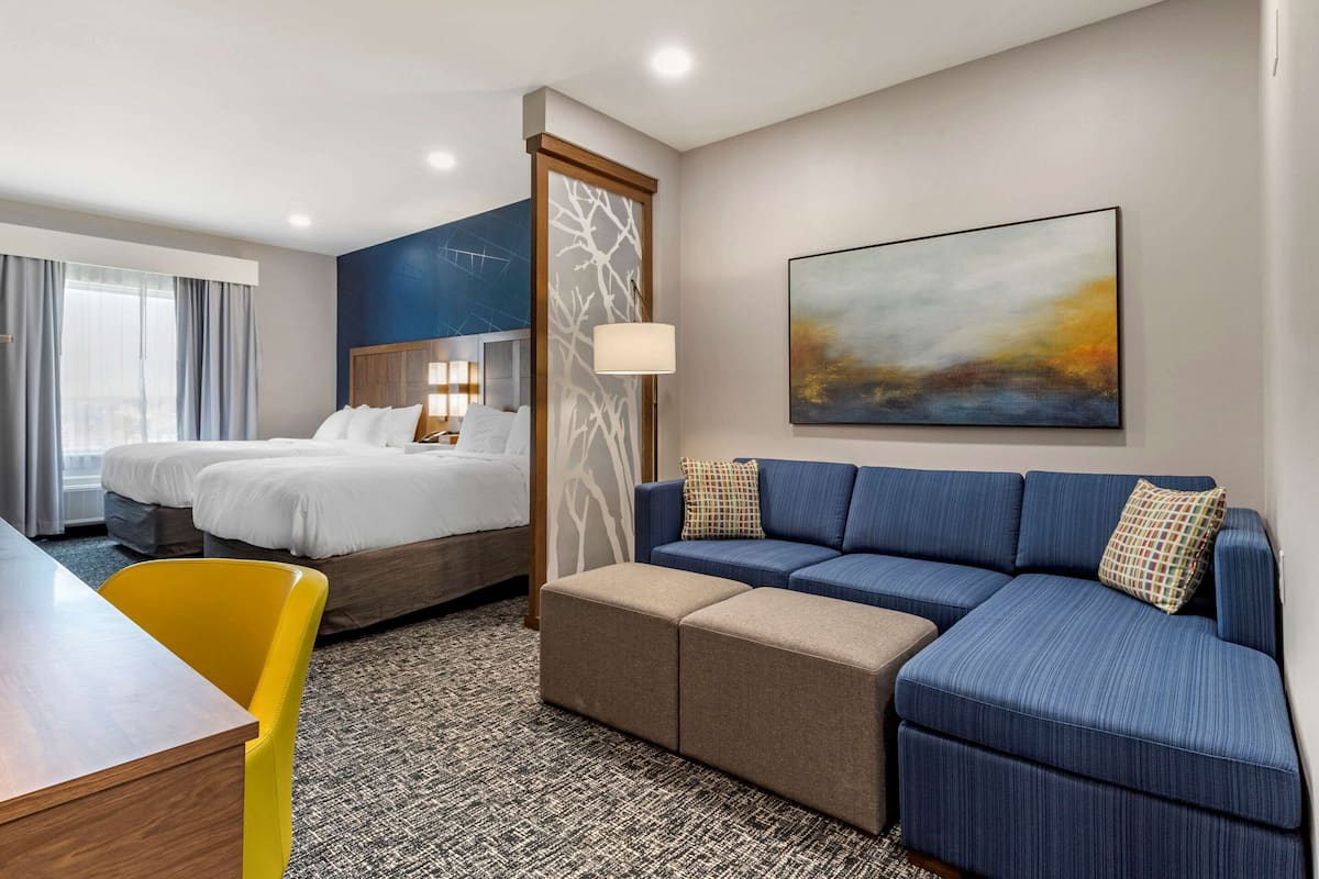 Een hotelkamer met een bed, een bank, een bureau en een schilderij aan de muur.