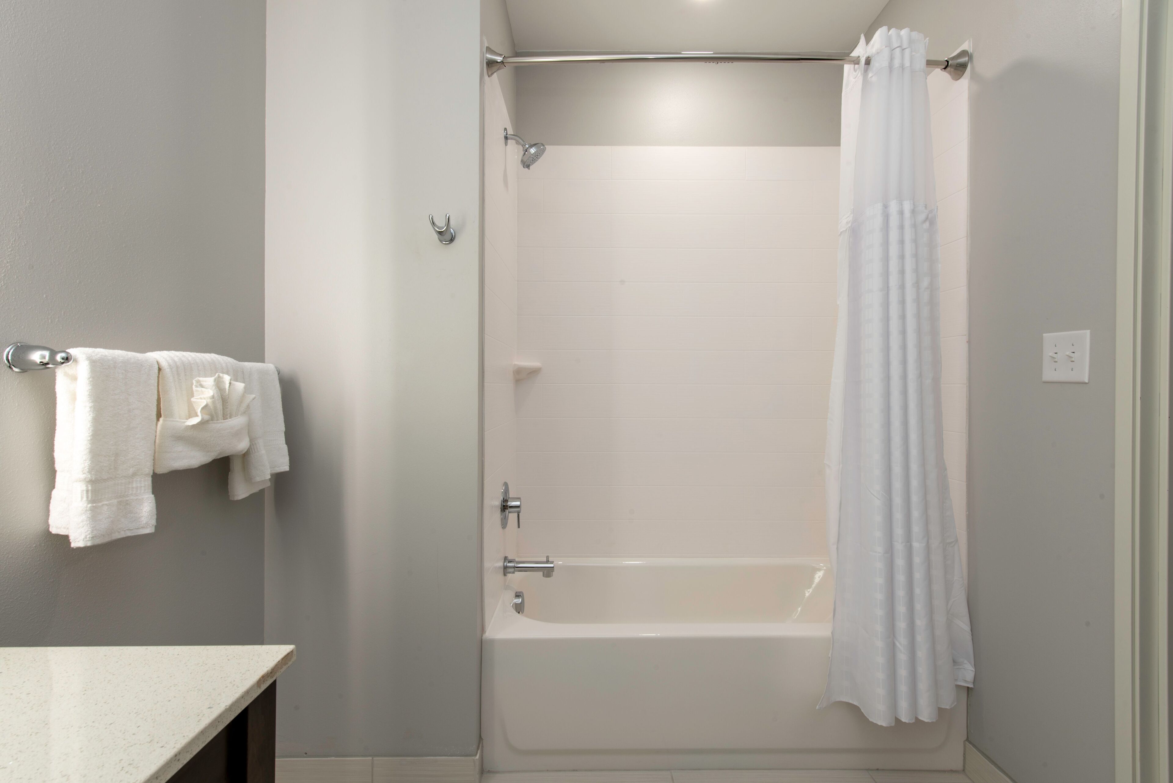 A bathroom with a bathtub, shower curtain, and towel rack.