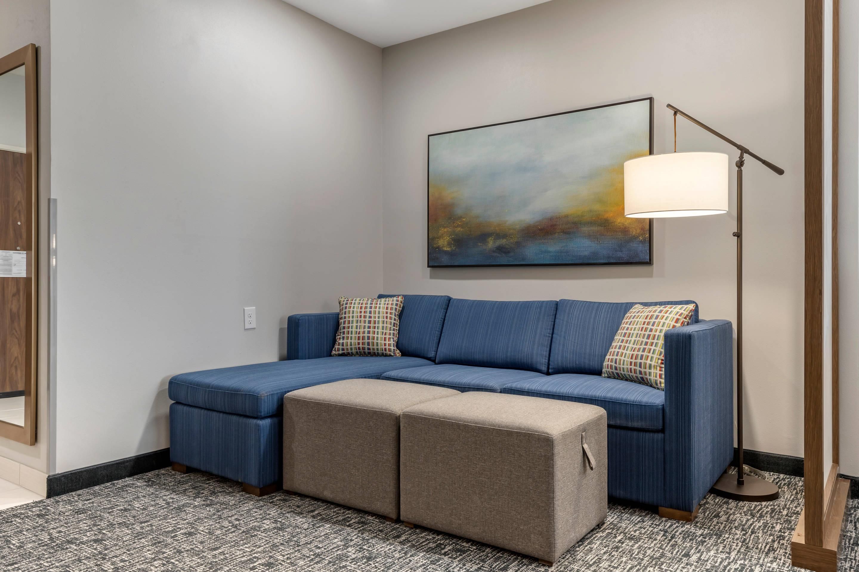A modern living room with a sectional sofa, a floor lamp, and a large abstract painting on the wall.