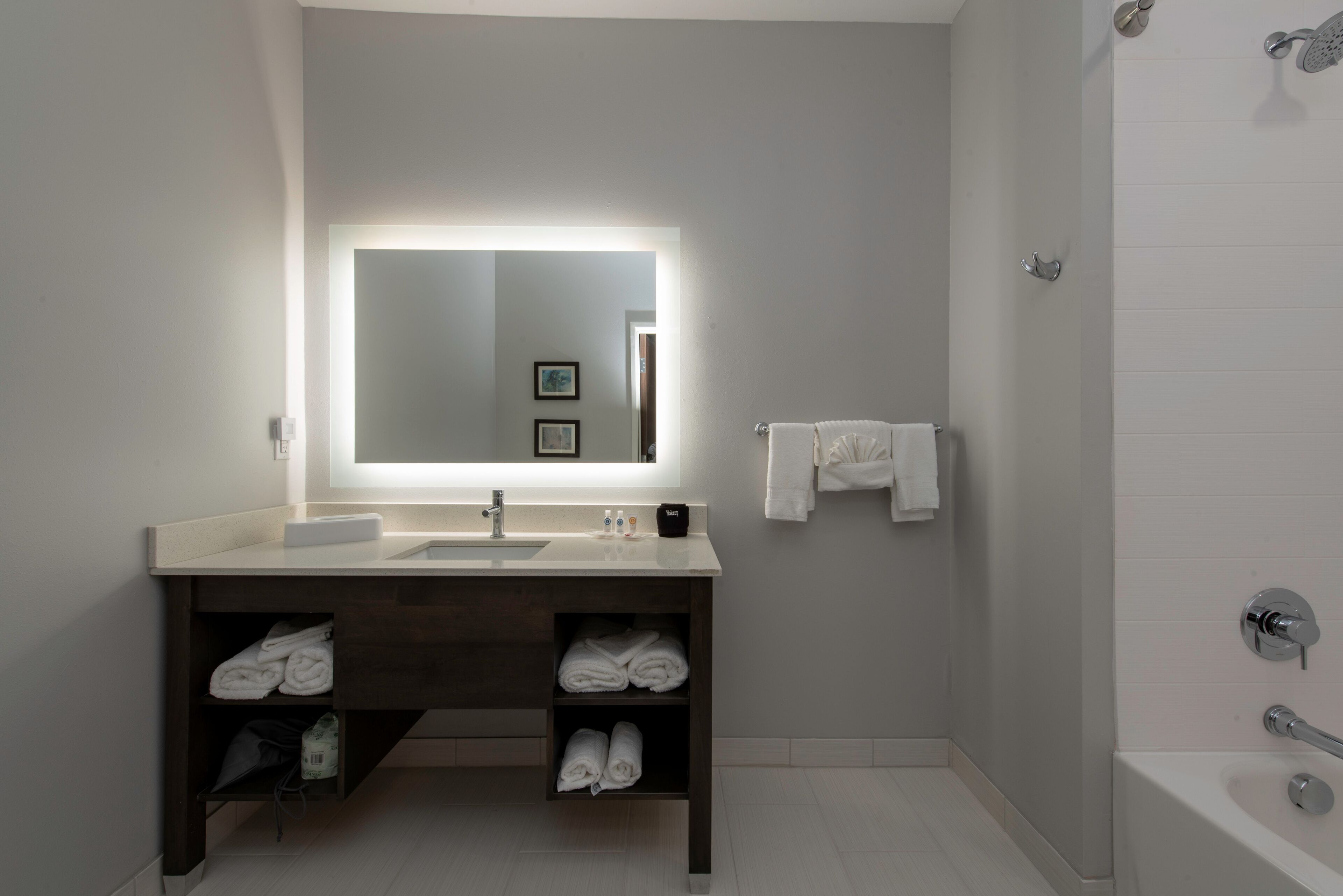 A modern bathroom with a large mirror, a sink, and a shower.