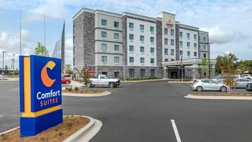 A Comfort Suites hotel with a modern building, a parking lot, and a signboard.