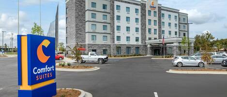 Un hotel Comfort Suites con un edificio moderno, un estacionamiento y un cartel.