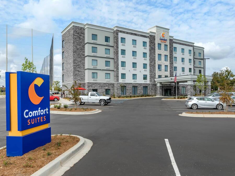 A Comfort Suites hotel with a modern building, a parking lot, and a signboard.
