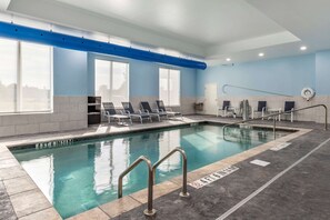An indoor swimming pool with clear blue water, a blue ceiling, and a tiled floor. There are lounge chairs and a pool ladder. - Comfort Suites Greenville Airport (Greenville)
