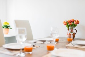 A dining table set with plates, glasses, and a pitcher of orange juice. - Freedom Gdansk Apartment (Gdansk)