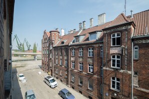 A row of red brick buildings with multiple windows and a dirt road in front. - Freedom Gdansk Apartment (Gdansk)