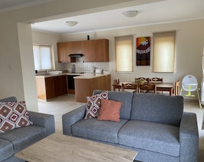 Una sala moderna con un sofá gris, una mesa de centro y una zona de comedor con muebles de madera.
