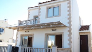 A two-story building with a balcony, a door, and a window. - Villa Ithaca Protaras (Paralimni)