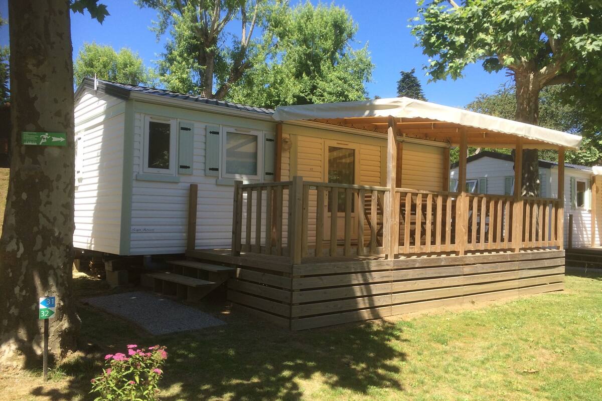 A mobile home with a covered porch and a small deck.
