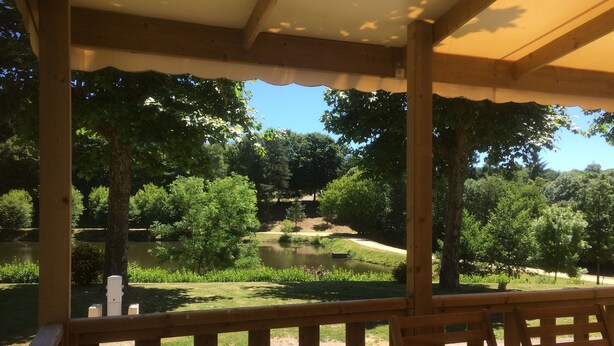 A wooden deck with a view of a lake and trees.