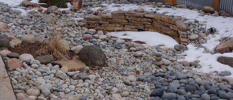 Stroll through the serene garden, surrounded by a circular pattern of stones and pebbles, and a small stone structure.