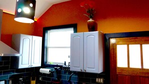 Una cucina con mobili bianchi, un lampadario nero e una finestra con vista.