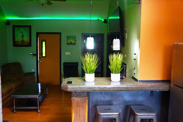 A bar area with stools, a counter, and two potted plants.