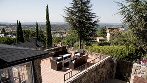 Eine Terrasse mit Gartenmöbeln, Steinmauern und Blick auf die umliegende Landschaft.