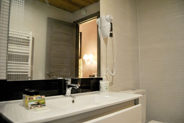 A bathroom with a white sink, a mirror, a hairdryer, and a towel rack.