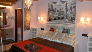 Ein Schlafzimmer mit einem großen Bett, einem Spiegel, einem Kleiderschrank, einem Nachttisch und einer Wandlampe.