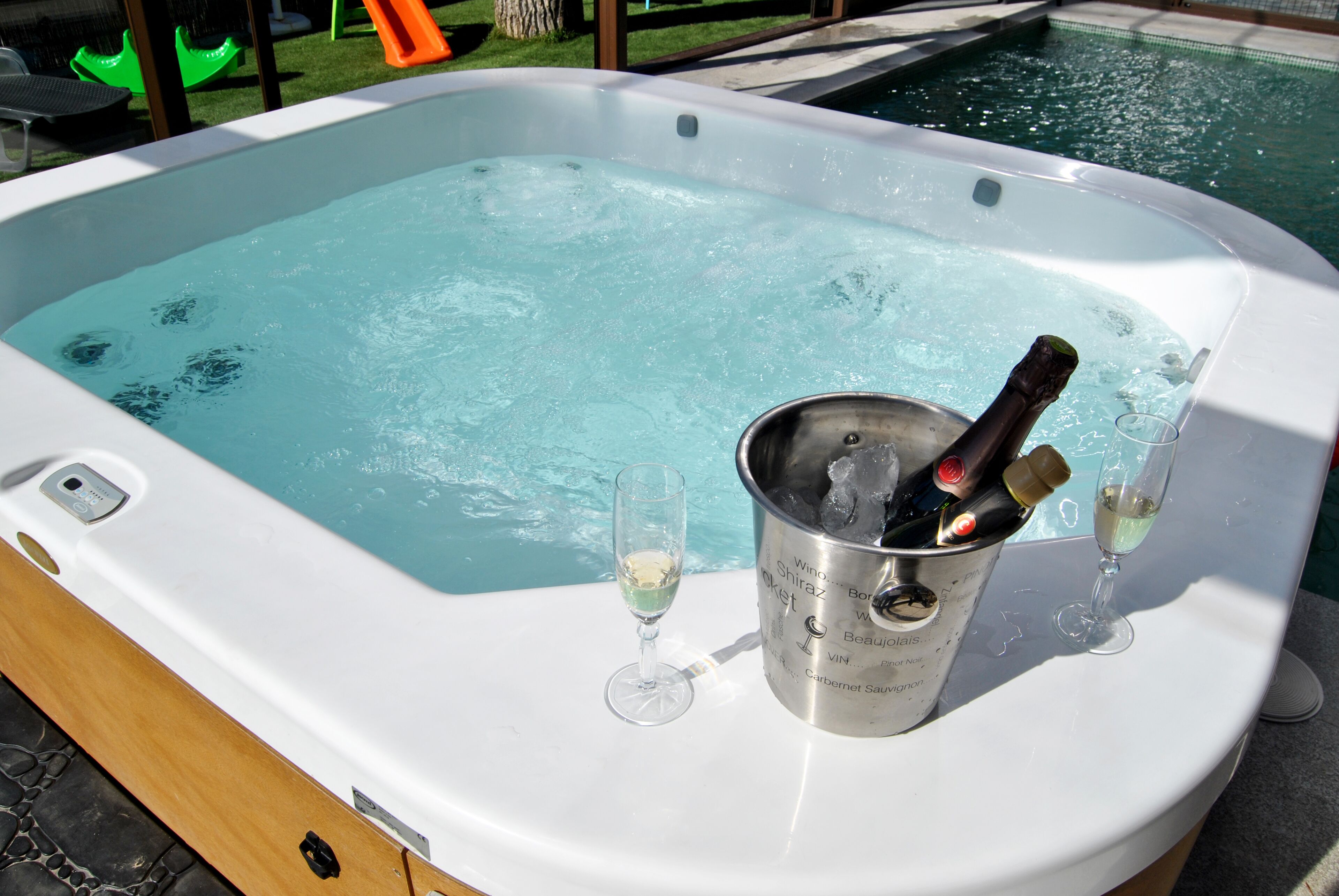 Un jacuzzi con un cubo de champán y copas.