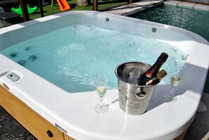 A hot tub with a champagne bucket and glasses. - Casas Rurales Collarubio (Collado Mediano)