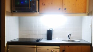 Une cuisine compacte dotée d’armoires en bois, d’un four à micro-ondes, d’un lave-vaisselle et d’un évier.