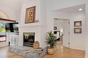 Cozy up by the fireplace in this inviting living room, featuring a flat-screen TV and a decorative piece above.