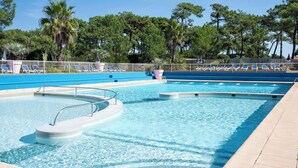 A swimming pool with a diving board, lounge chairs, and a fenced area with trees in the background. - Belambra Clubs Capbreton - Les Vignes (Capbreton)