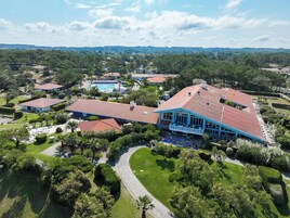 Vista aérea de un complejo turístico con piscina, varias edificaciones y jardines cuidados.