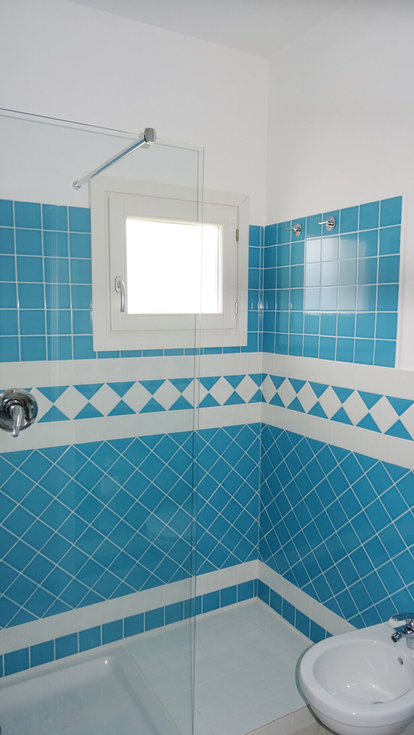 Ein Badezimmer mit blauen und weißen Fliesen, einem weißen Waschbecken und einer Duschkabine.