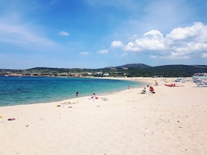 A beach with clear blue water, sandy shore, and a few people. - Affittimoderni Isola Rossa Élite - Pati19 (Trinità d'Agultu e Vignola)