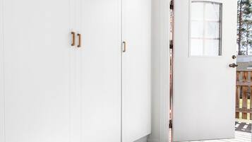 A modern interior with white walls, a grey floor, and a door leading outside.