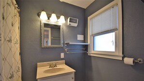 Ein Badezimmer mit Waschbecken, Spiegel, Handtuchhalter, Fenster und Toilette.